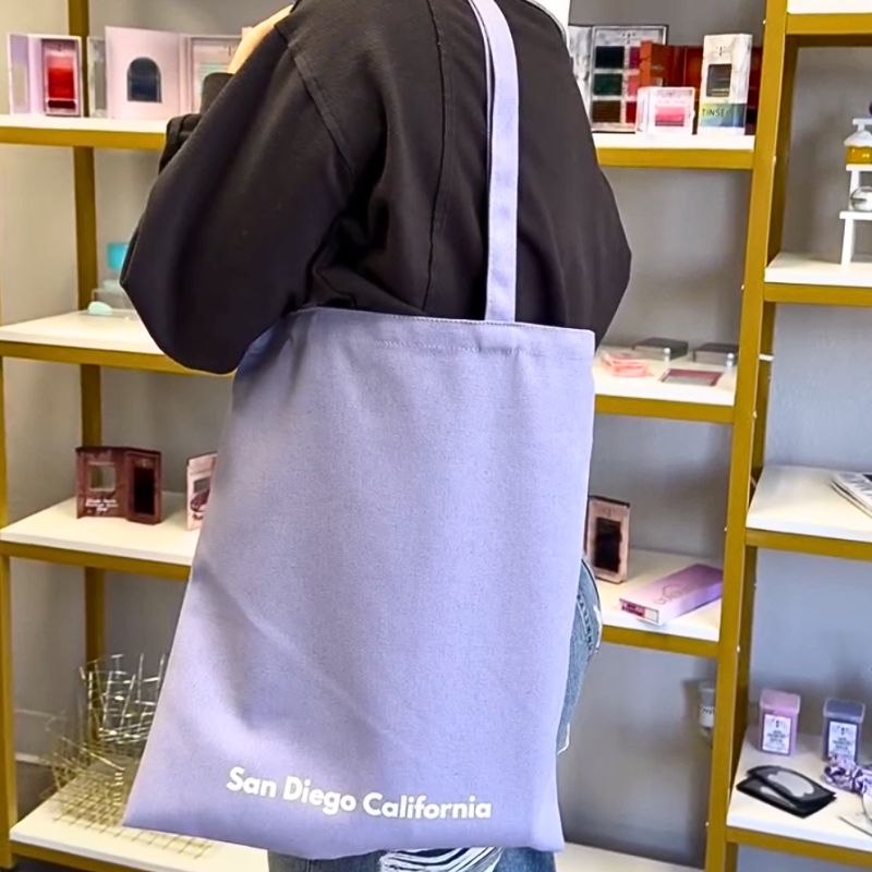 Back view of purple Local Lash Plug tote bag inside a lash studio with durable straps for carrying lash supplies and tools