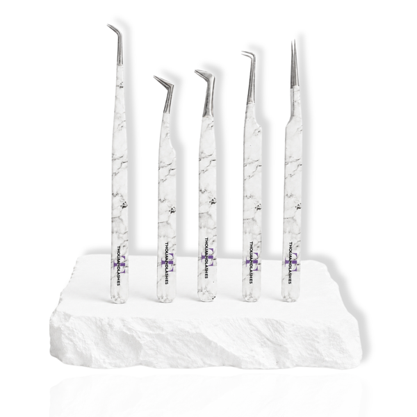 Beginner's Eyelash Tweezers Kit featuring five white marble-pattern lash tweezers with different angled tips displayed on a white stone surface.