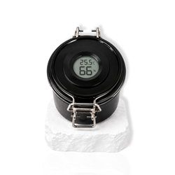 Black lash glue storage container with digital humidity display on the lid displayed on a white stone surface.