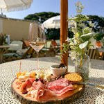 Charcuterie board with cheese, fruit, and wine arranged on an outdoor table at a wellness event.