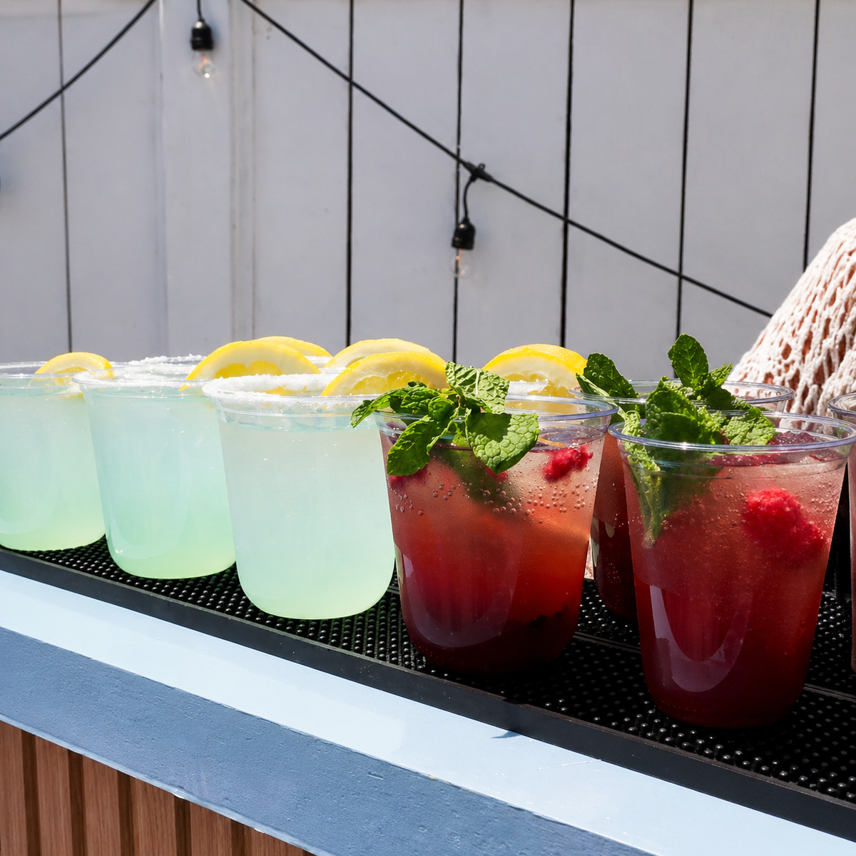 Colorful fresh drinks displayed on a counter during an outdoor event.