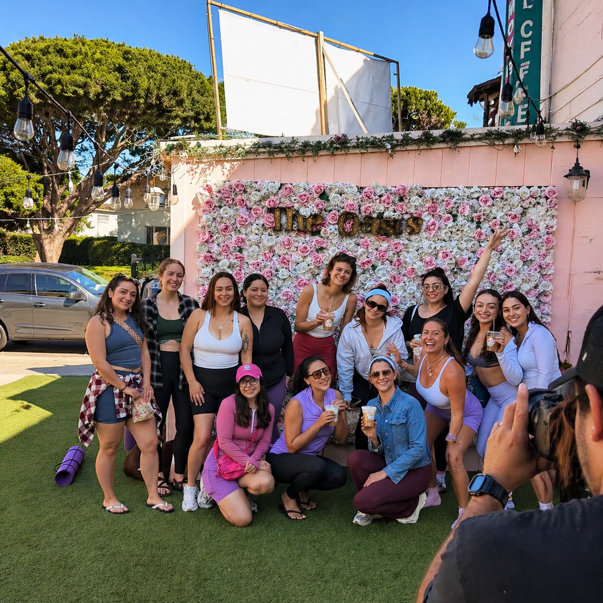 Group of attendees posing together in front of a floral photo backdrop at a wellness event.