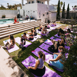 Group of attendees practicing yoga poses on mats during an outdoor wellness event.