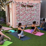 Guests doing yoga and stretching exercises in front of a floral backdrop.