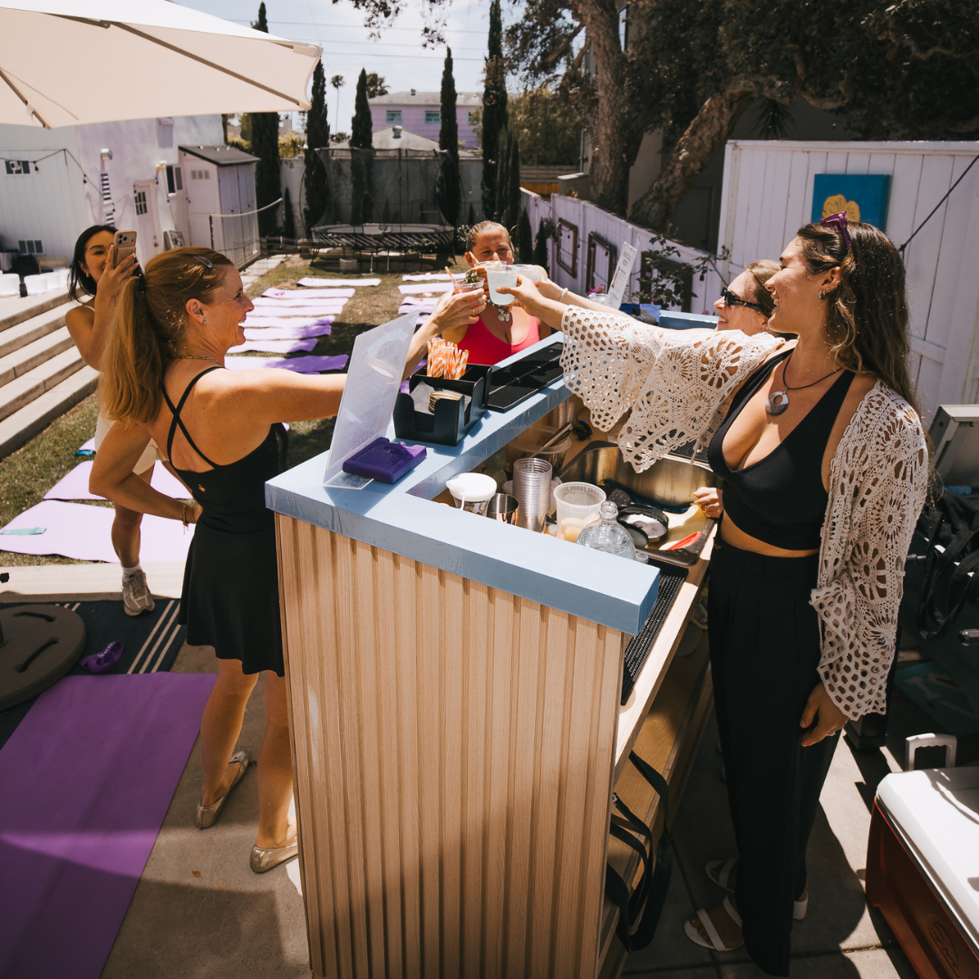 Guests enjoying drinks and conversations at an outdoor event bar area.