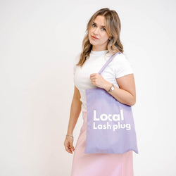 Lash artist wearing a purple Local Lash Plug tote bag while showcasing a stylish carry bag for lash supplies and beauty essentials