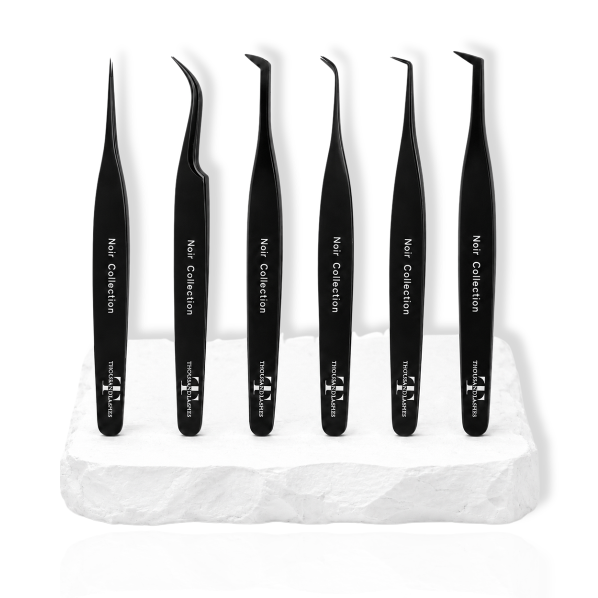 Noir Collection lash tweezer set featuring six black lash tweezers displayed on a white stone surface.