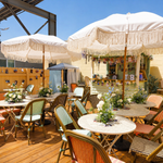Outdoor wellness event setup with tables, chairs, umbrellas, and floral decorations on a patio.
