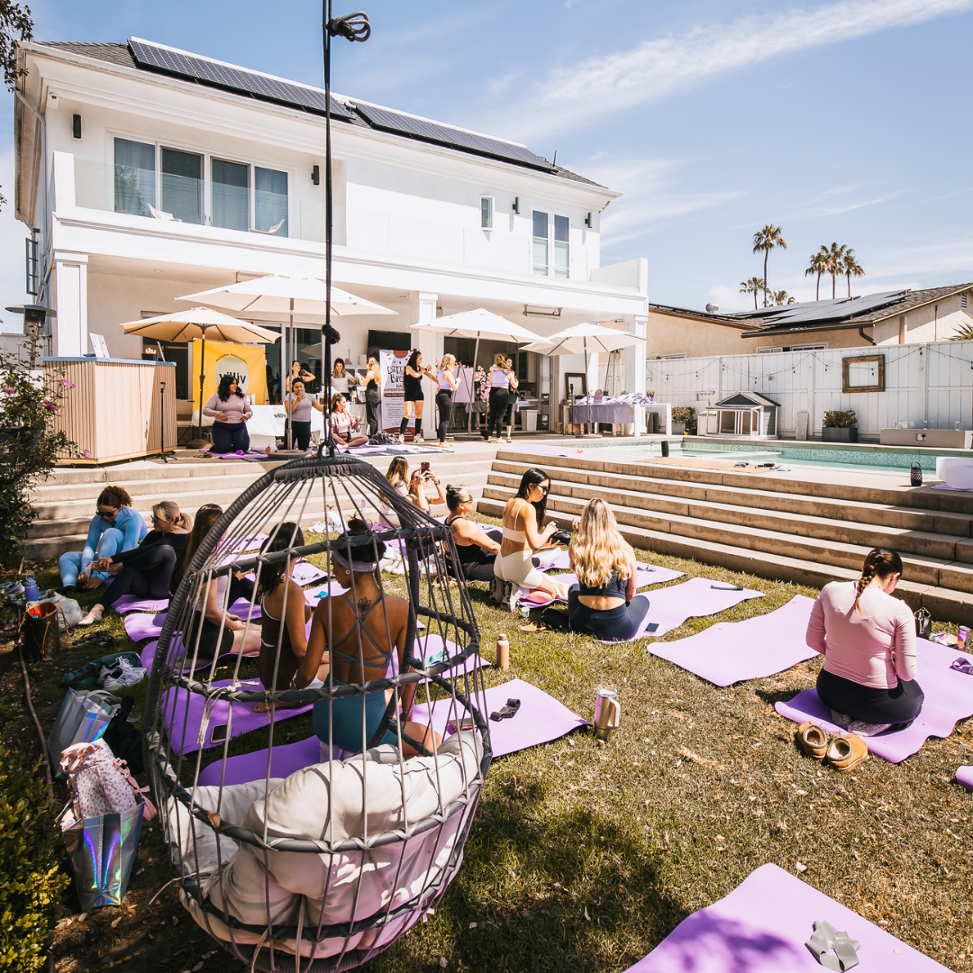 Outdoor wellness event setup with yoga mats, seating areas, and attendees gathering.