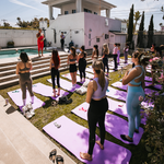 Participants relaxing on yoga mats beside a pool during a wellness session.