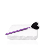 Purple eyelash extension mirror with a black heart-shaped head displayed on a white stone surface.