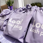 Purple swag bags prepared for attendees at a lash artist wellness event.