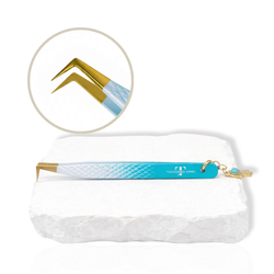 Thousandlashes Evil Eye angled lash tweezer with gold tip and Hamsa charm on a white stone surface.
