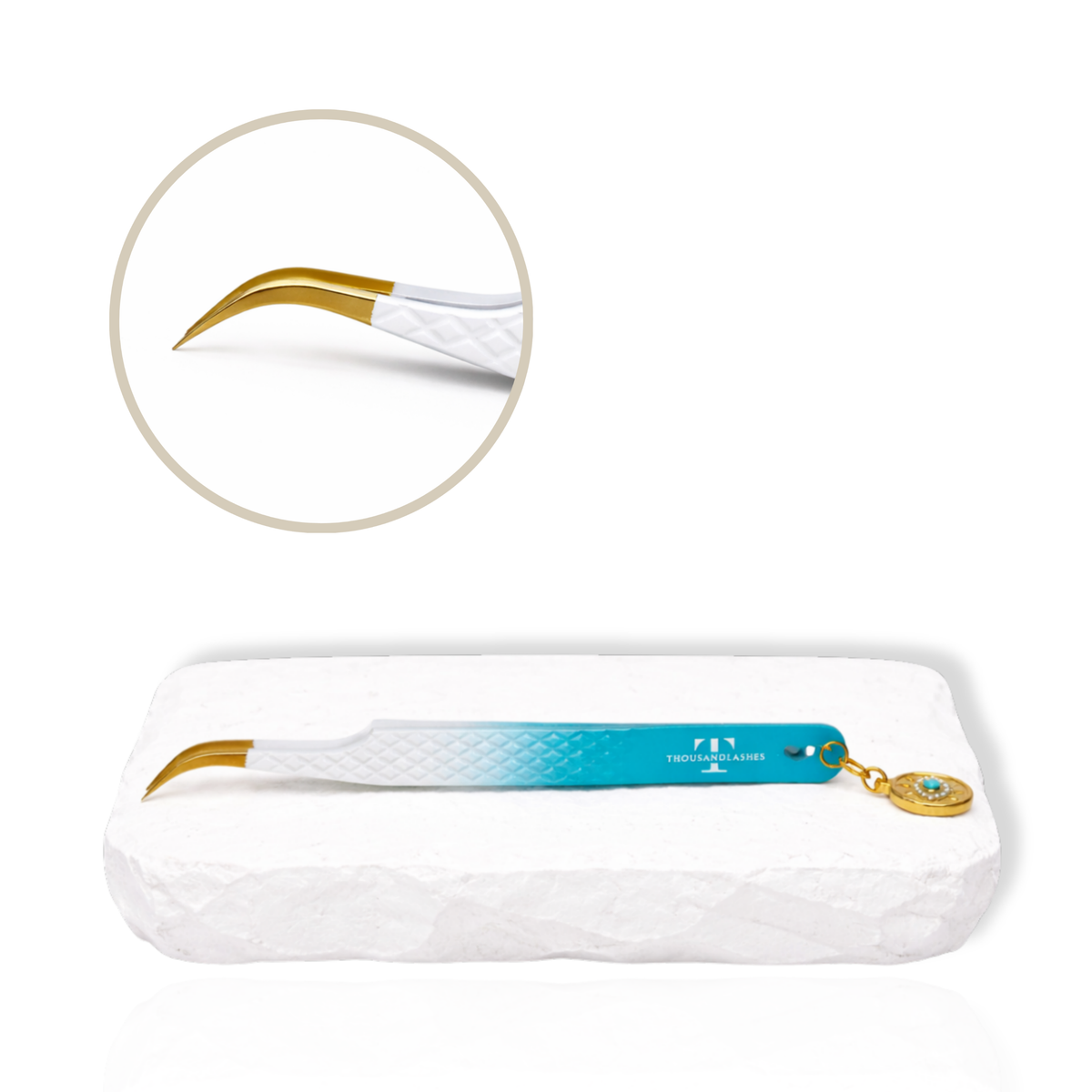Thousandlashes Evil Eye curved isolation tweezer with gold tip and decorative charm on a white stone surface.