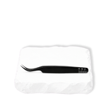 Thousandlashes Noir Collection curved tweezer shown from the reverse side on a white stone surface.