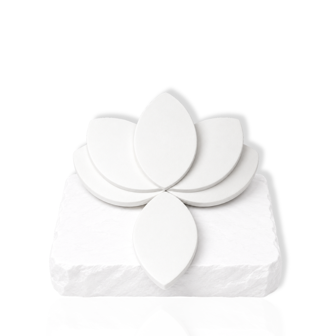 White leaf-shaped makeup sponges arranged on a white stone slab.