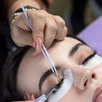 Lash artist using curved tweezer during eyelash extension application on a client