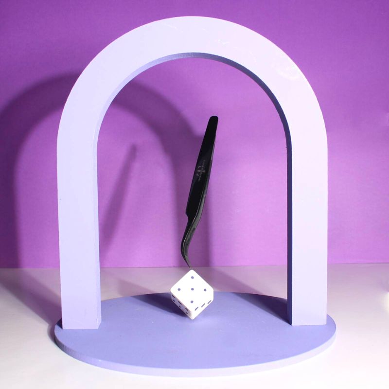 Thousandlashes Noir Collection curved tweezer displayed on a purple stand.